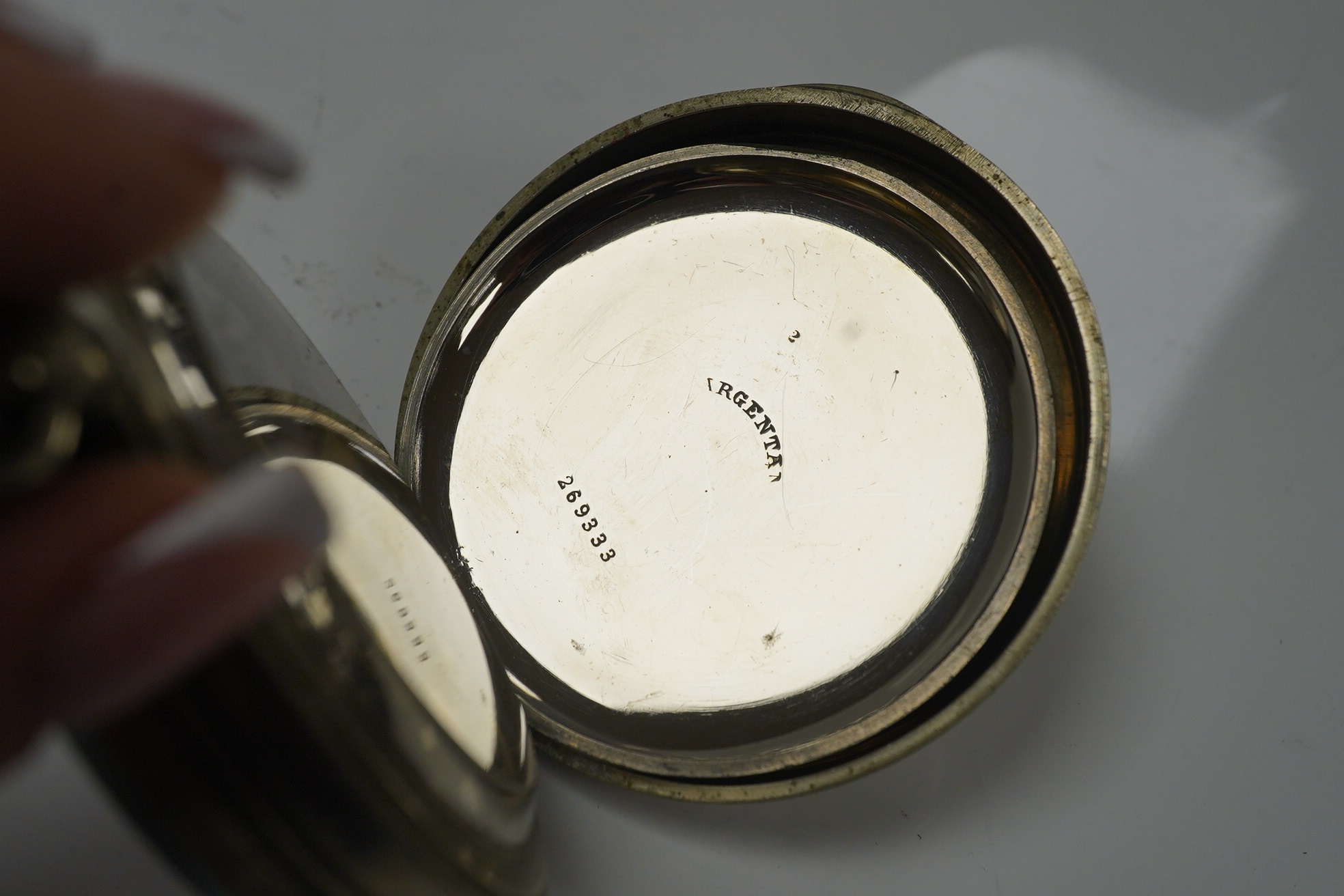 An Edwardian repousse silver mounted travelling watch case, maker W.?, Chester, 1902, 11.1cm, containing a nickel cased pocket watch. Condition - poor to fair